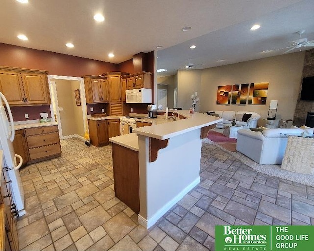 kitchen featuring open floor plan, a peninsula, white appliances, and stone tile flooring