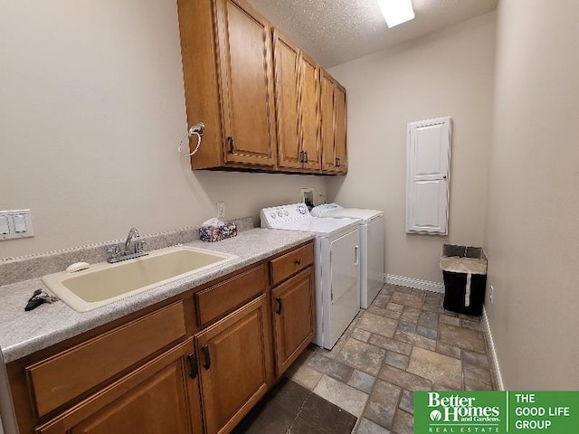 laundry area featuring cabinet space, stone tile floors, baseboards, separate washer and dryer, and a sink