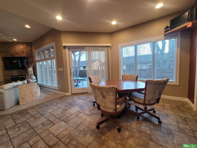 dining space featuring a fireplace, stone tile flooring, and baseboards