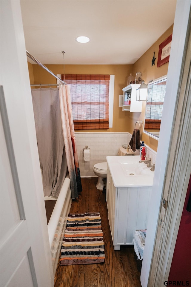 full bathroom with a wainscoted wall, tile walls, toilet, vanity, and wood finished floors