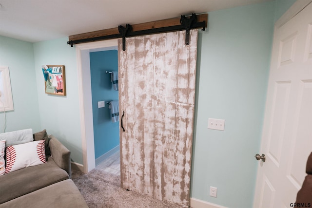 carpeted bedroom with a barn door and baseboards