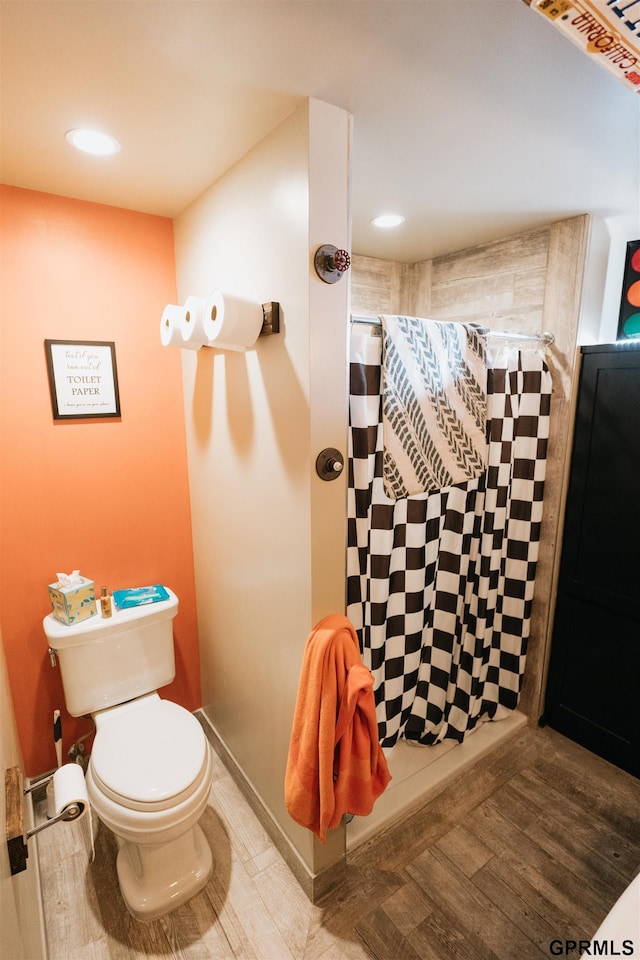 full bath featuring tiled shower, wood finished floors, toilet, and recessed lighting