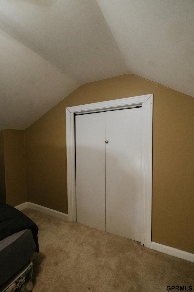 carpeted bedroom with baseboards and vaulted ceiling