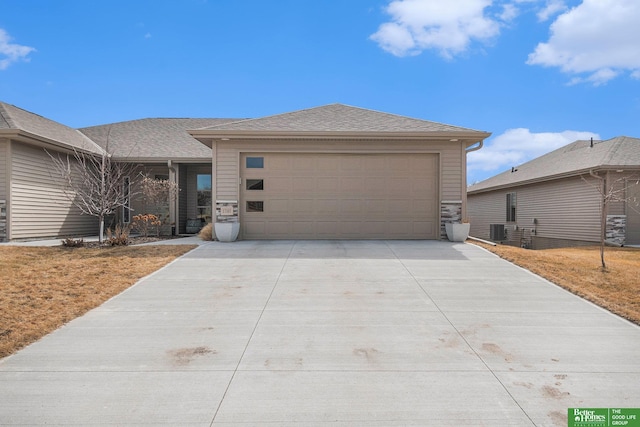 view of front of house with driveway, a shingled roof, an attached garage, and cooling unit