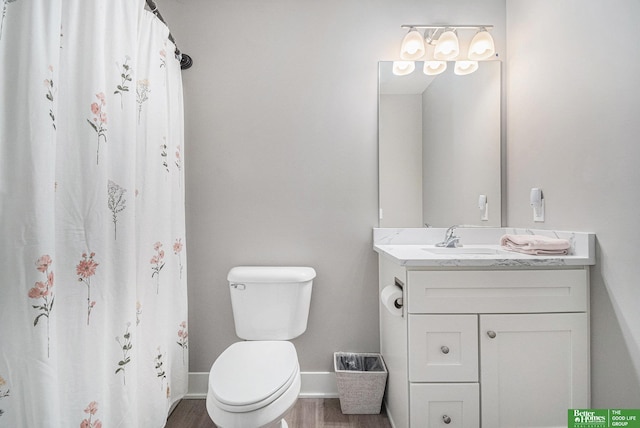 bathroom with toilet, vanity, wood finished floors, a shower with curtain, and baseboards