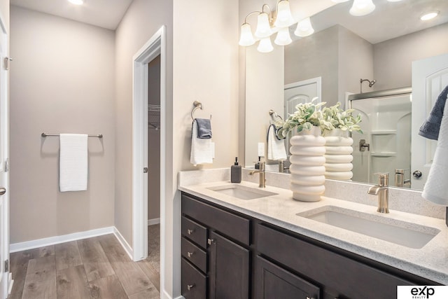 bathroom featuring double vanity, a sink, a shower stall, and wood finished floors