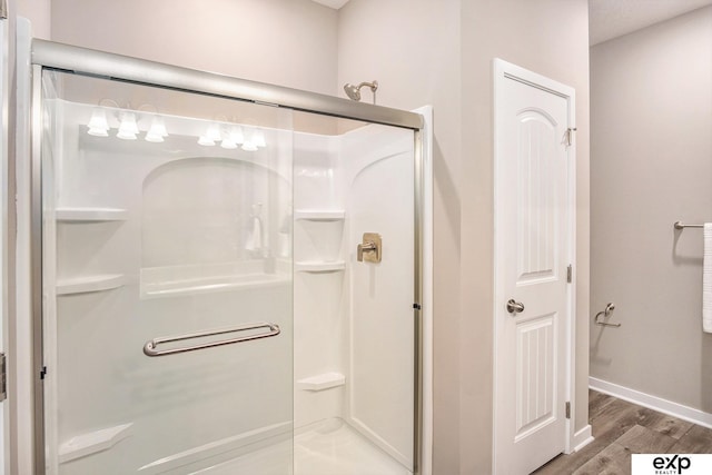 full bathroom with a shower stall, baseboards, and wood finished floors