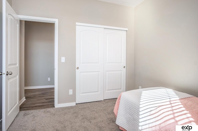 carpeted bedroom featuring a closet and baseboards