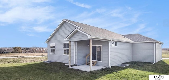 back of property featuring a shingled roof and a lawn