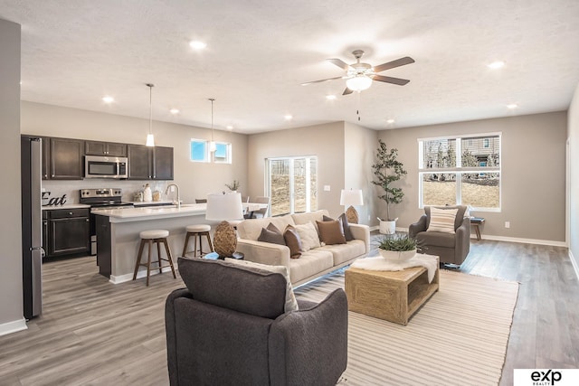 living room featuring light wood-style floors, recessed lighting, plenty of natural light, and baseboards