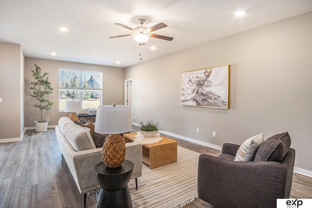 living area with recessed lighting, a ceiling fan, a textured ceiling, wood finished floors, and baseboards