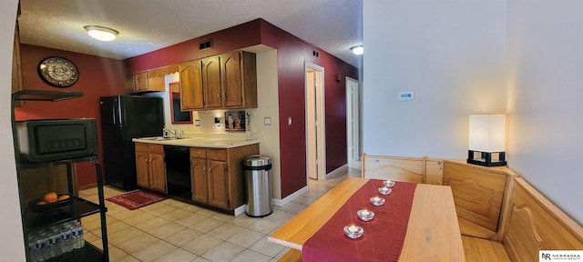 kitchen with light tile patterned floors, light countertops, visible vents, a textured ceiling, and black appliances