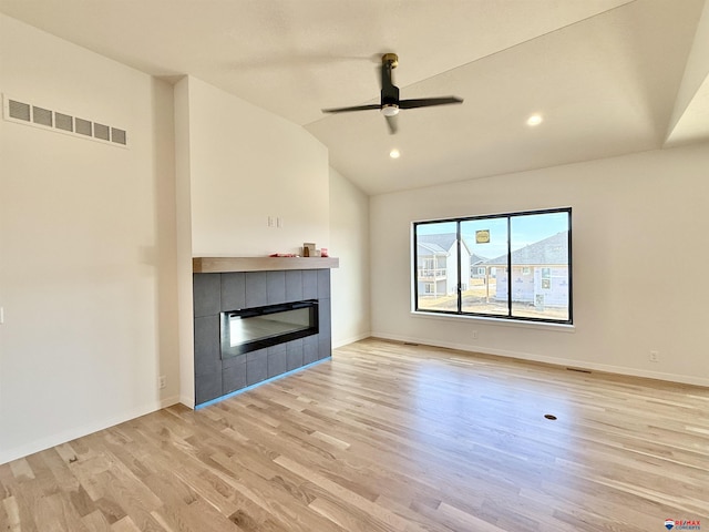 unfurnished living room featuring light wood finished floors, baseboards, visible vents, lofted ceiling, and a fireplace