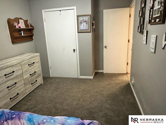 bedroom with dark colored carpet and baseboards