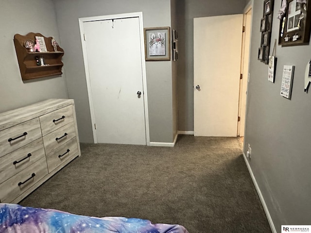 bedroom featuring dark carpet and baseboards