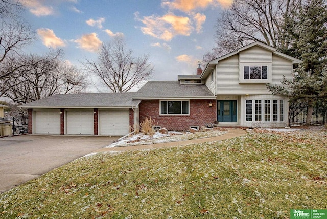 traditional home featuring a garage, driveway, brick siding, fence, and a front yard