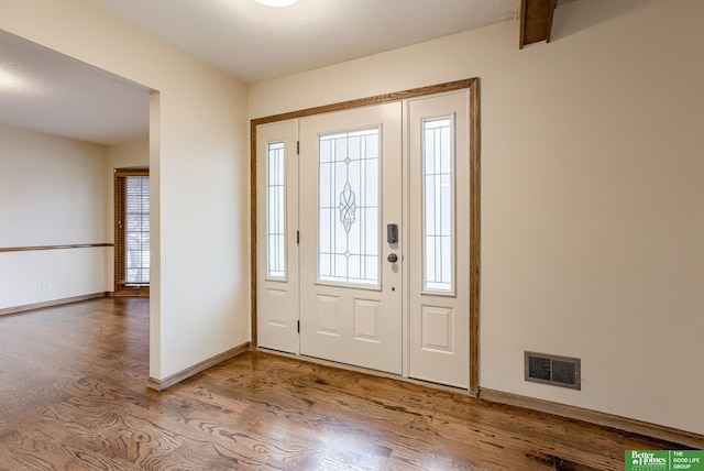 entryway featuring wood finished floors, visible vents, and baseboards