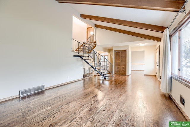 unfurnished living room with baseboards, visible vents, stairway, beamed ceiling, and wood finished floors