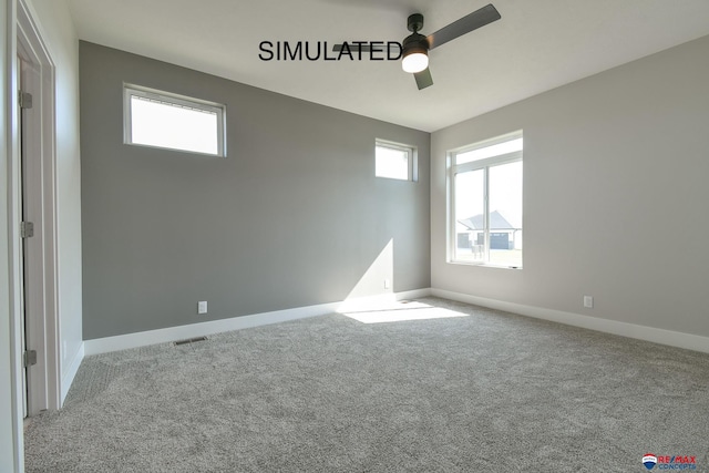 carpeted empty room featuring a ceiling fan, plenty of natural light, visible vents, and baseboards