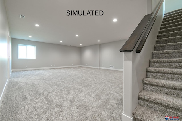 below grade area featuring carpet floors, recessed lighting, visible vents, stairway, and baseboards