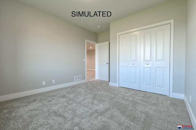 unfurnished bedroom with carpet floors, a closet, visible vents, and baseboards