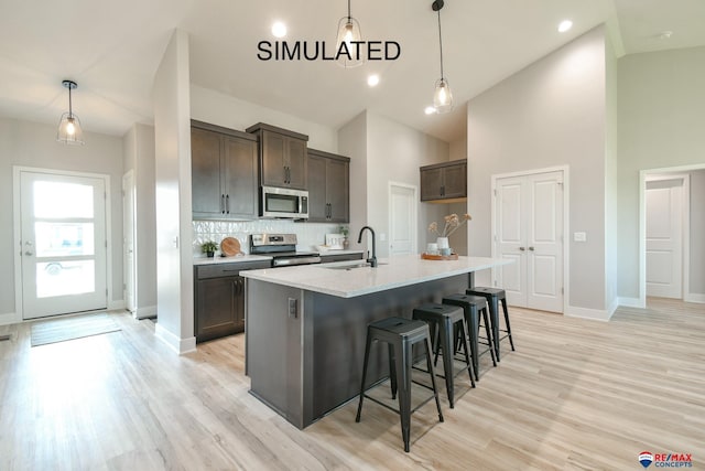 kitchen featuring stainless steel appliances, light wood finished floors, a sink, and dark brown cabinetry