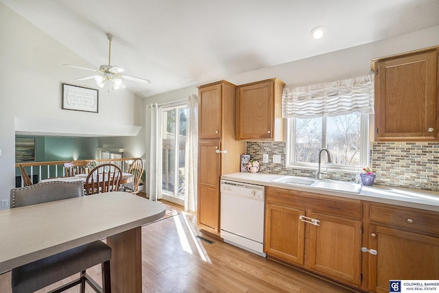 kitchen with ceiling fan, light countertops, vaulted ceiling, white dishwasher, and a sink