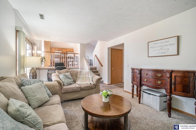 living area with stairs, visible vents, baseboards, and light carpet