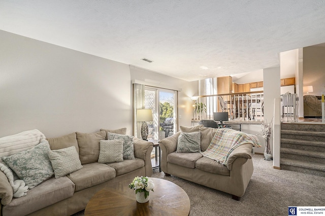 living room with light carpet, visible vents, a textured ceiling, and stairs