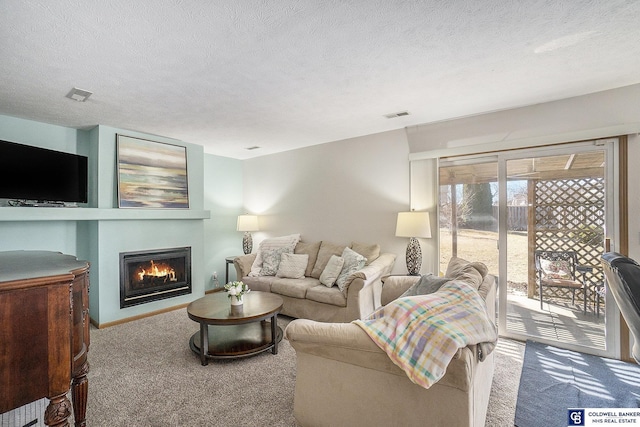 carpeted living room with visible vents, a lit fireplace, and a textured ceiling