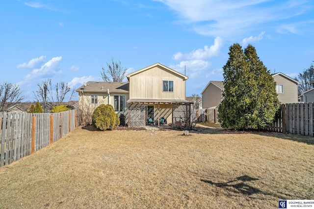 back of house with a yard and a fenced backyard