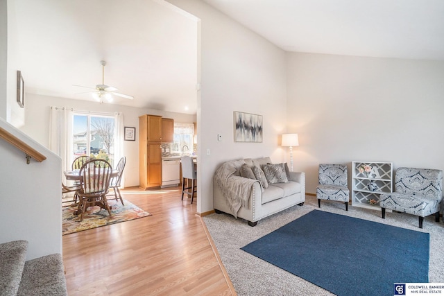 living room featuring stairway, lofted ceiling, light wood-style flooring, and a ceiling fan