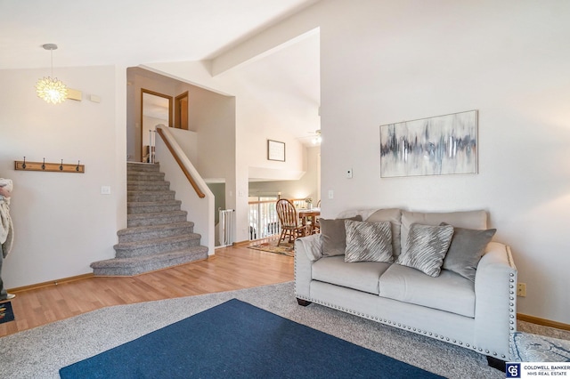 living area with high vaulted ceiling, a ceiling fan, wood finished floors, stairway, and carpet floors