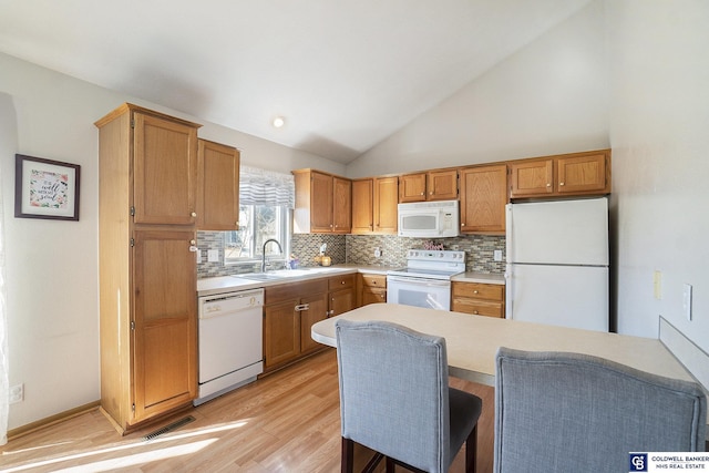 kitchen featuring visible vents, a sink, white appliances, light countertops, and decorative backsplash