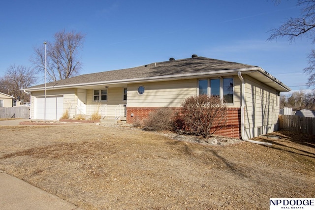 ranch-style home with a garage, fence, and brick siding