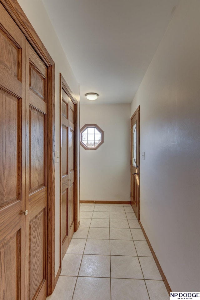 corridor featuring light tile patterned flooring and baseboards