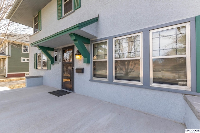 view of exterior entry with a patio and stucco siding