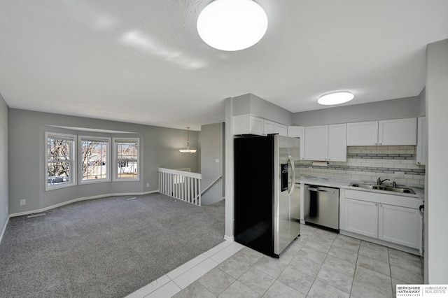 kitchen featuring a sink, stainless steel appliances, light carpet, and white cabinets