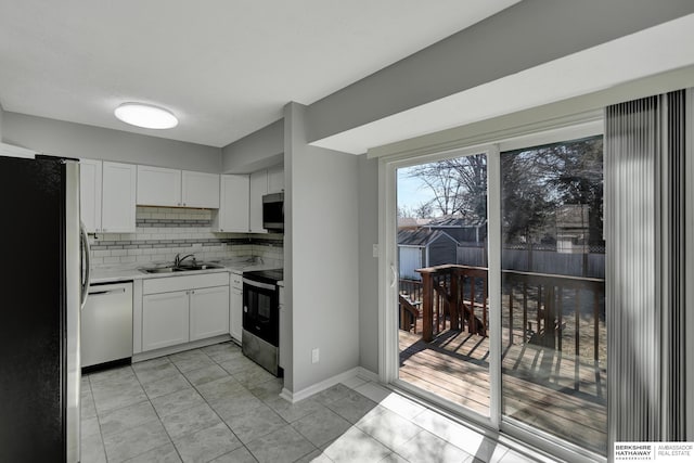 kitchen featuring a sink, decorative backsplash, light countertops, white cabinets, and appliances with stainless steel finishes