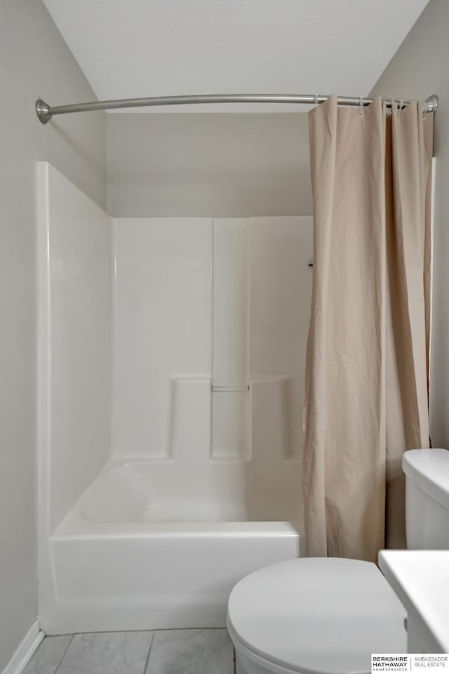 bathroom featuring tile patterned floors, shower / bath combo with shower curtain, toilet, and vanity