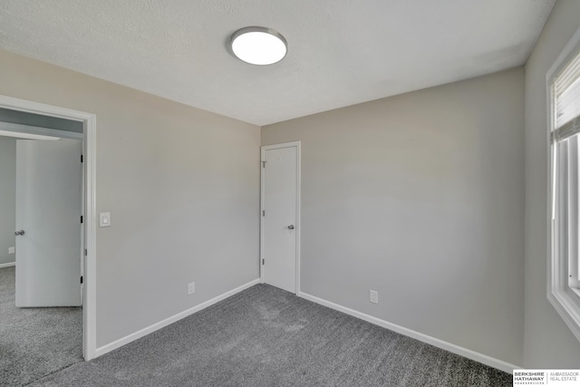 unfurnished room with baseboards, a textured ceiling, and carpet flooring