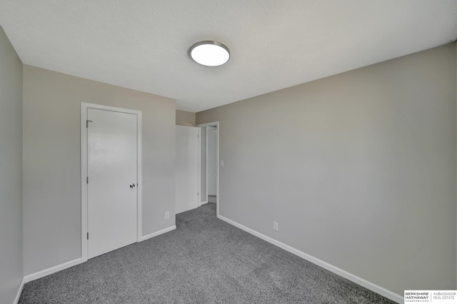 unfurnished bedroom featuring dark carpet and baseboards