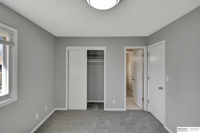 unfurnished bedroom featuring a closet, multiple windows, baseboards, and carpet