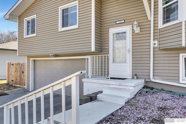 doorway to property featuring an attached garage and fence