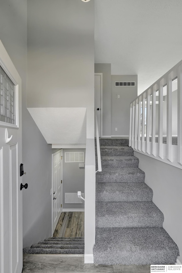 stairway with visible vents and wood finished floors