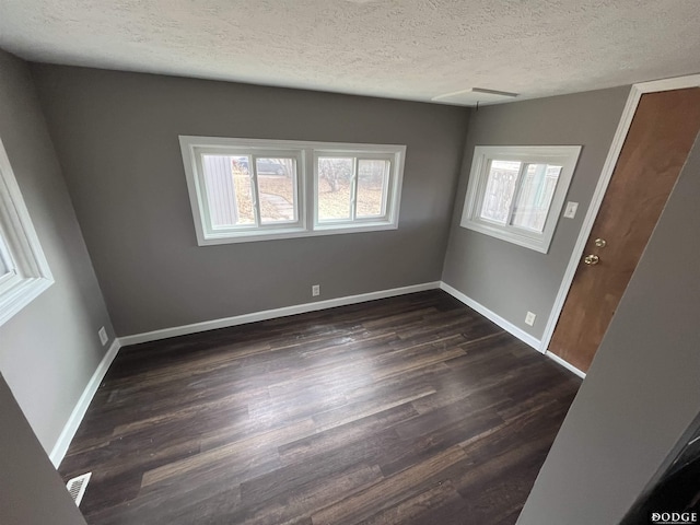 interior space featuring visible vents, baseboards, dark wood finished floors, and a textured ceiling