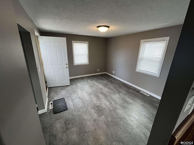 unfurnished bedroom featuring a textured ceiling, dark wood-type flooring, visible vents, and baseboards