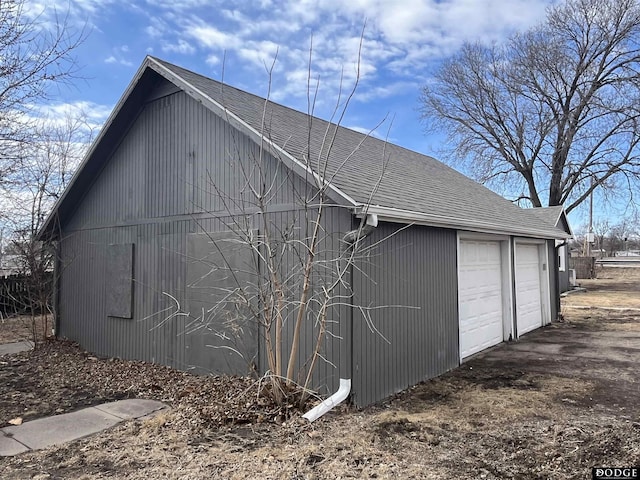 view of side of home featuring a shingled roof and an outbuilding