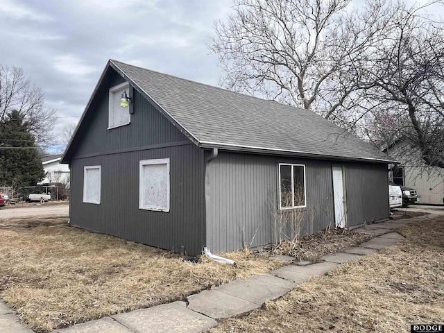 view of side of home with roof with shingles