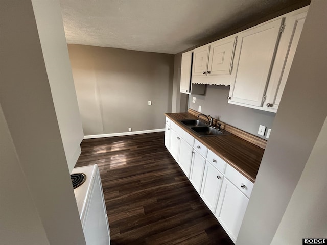 kitchen featuring white electric range, dark wood-type flooring, white cabinetry, a sink, and baseboards